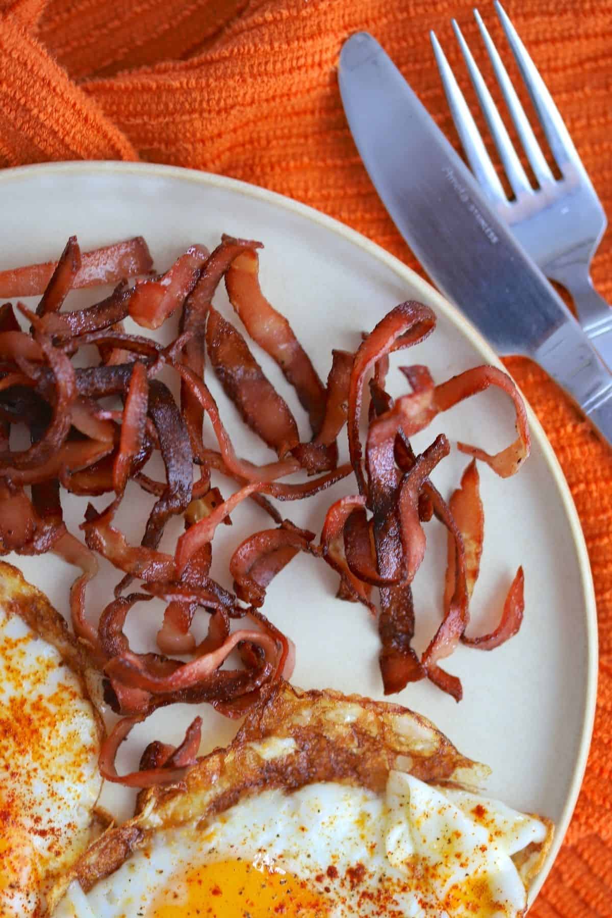 fried mortadella with eggs, cutlery on an orange napkin.