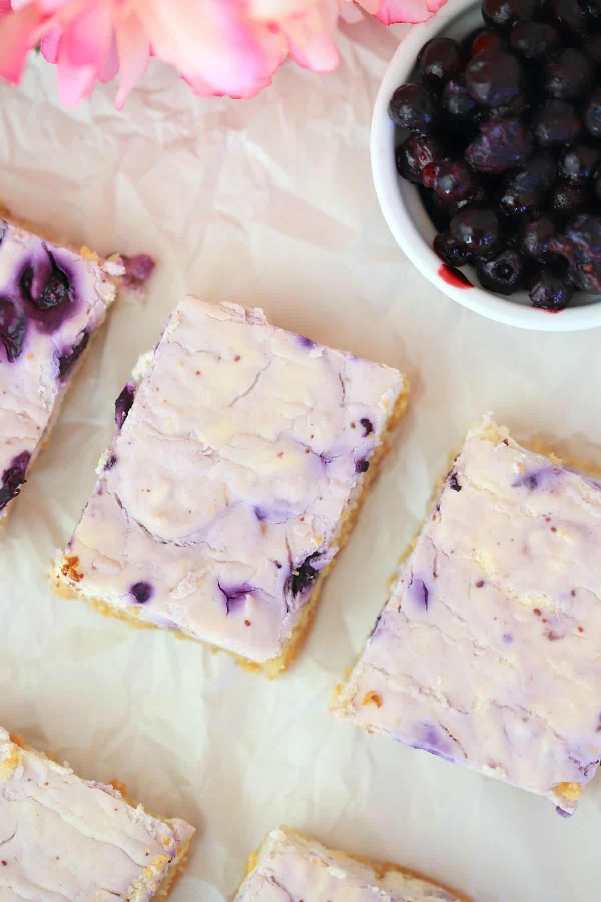 overhead shot of cheesecake bars with a bowl of blueberries