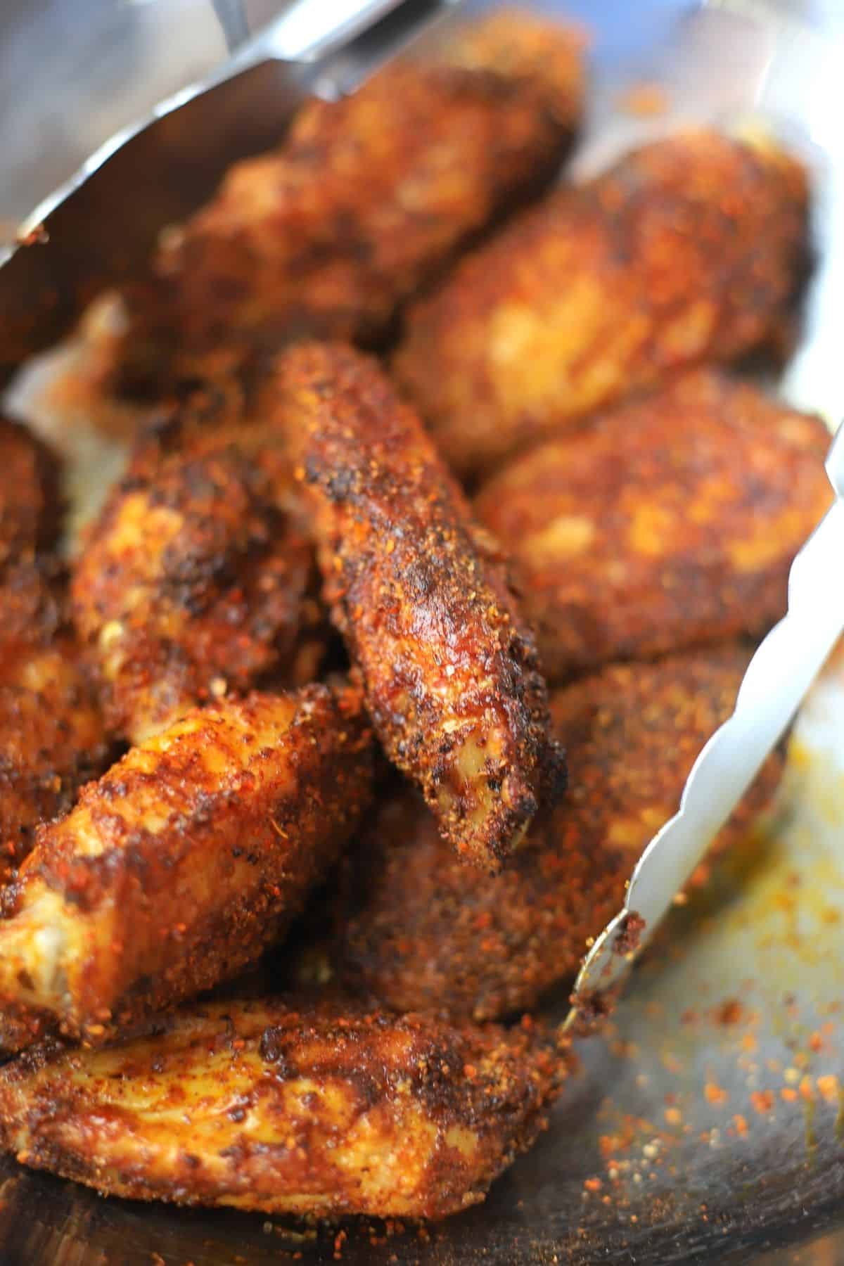 tossing chicken wings with tajin seasoning.