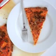 slice of pizza on a white plate with a fork.