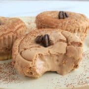 three mini cheesecakes on a plate topped with coffee beans.