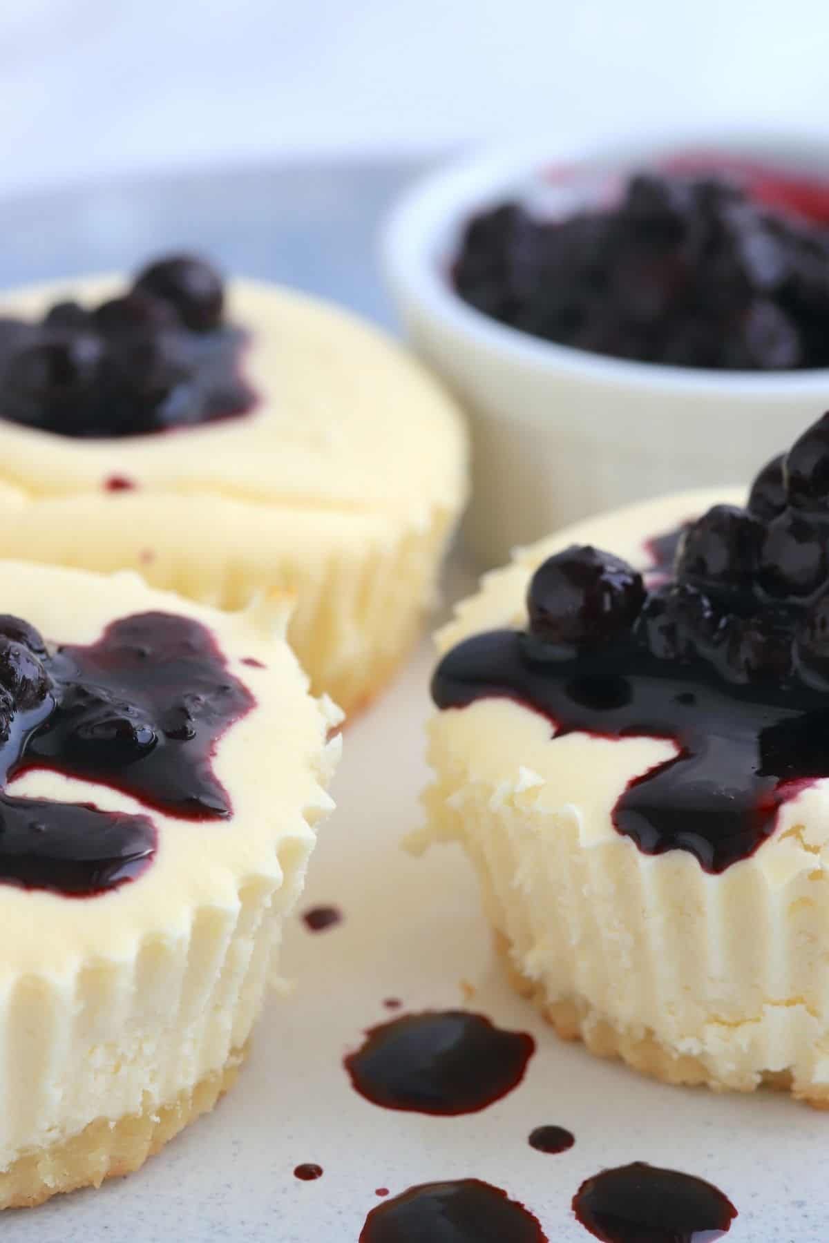 keto cheesecake cupcakes topped with blueberries and a side bowl of blueberries