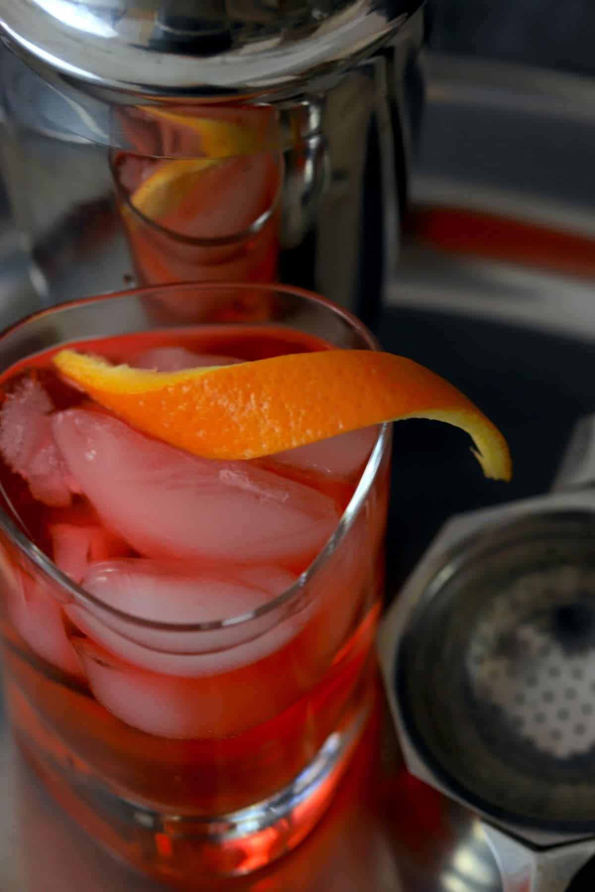 negroni cocktail with strainer and orange twist..