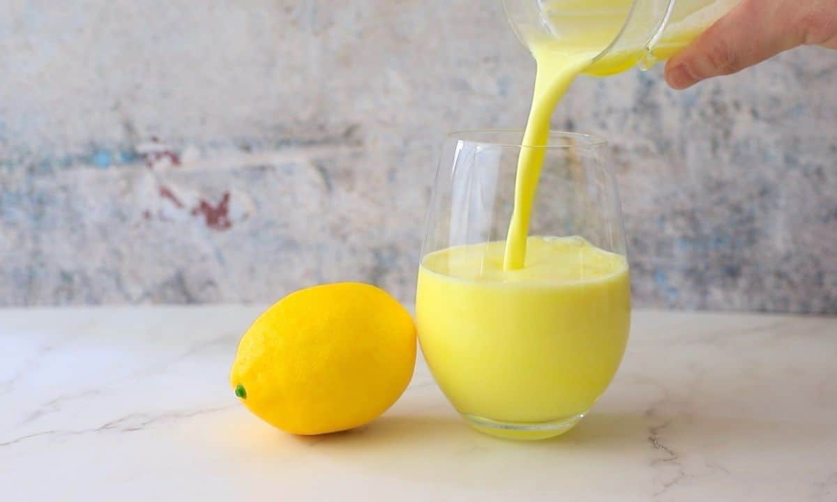 pouring the sugar free electrolyte smoothie into a glass next to a whole lemon.