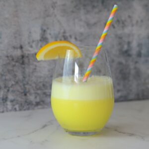 a glass with a foamy sugar free lemonade electrolyte smoothie with a lemon wedge and a straw.