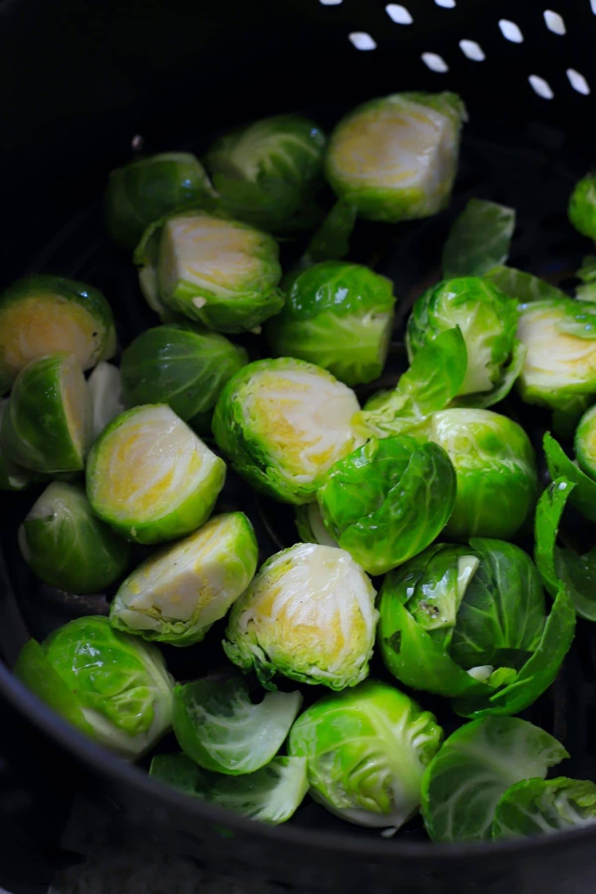 fresh cut brussel sprouts in the air fryer basket.