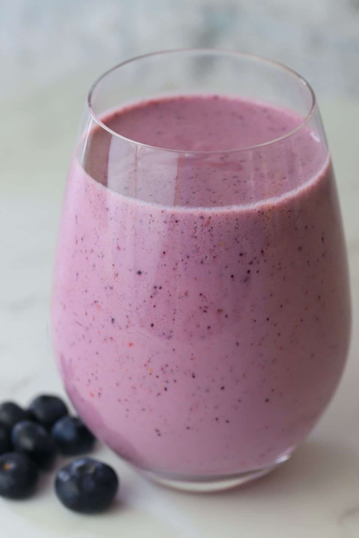 low carb berry smoothie in a clear glass next to blueberries.