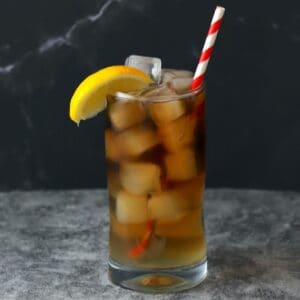 highball glass low carb long island iced tea, lemon garnish and a straw.