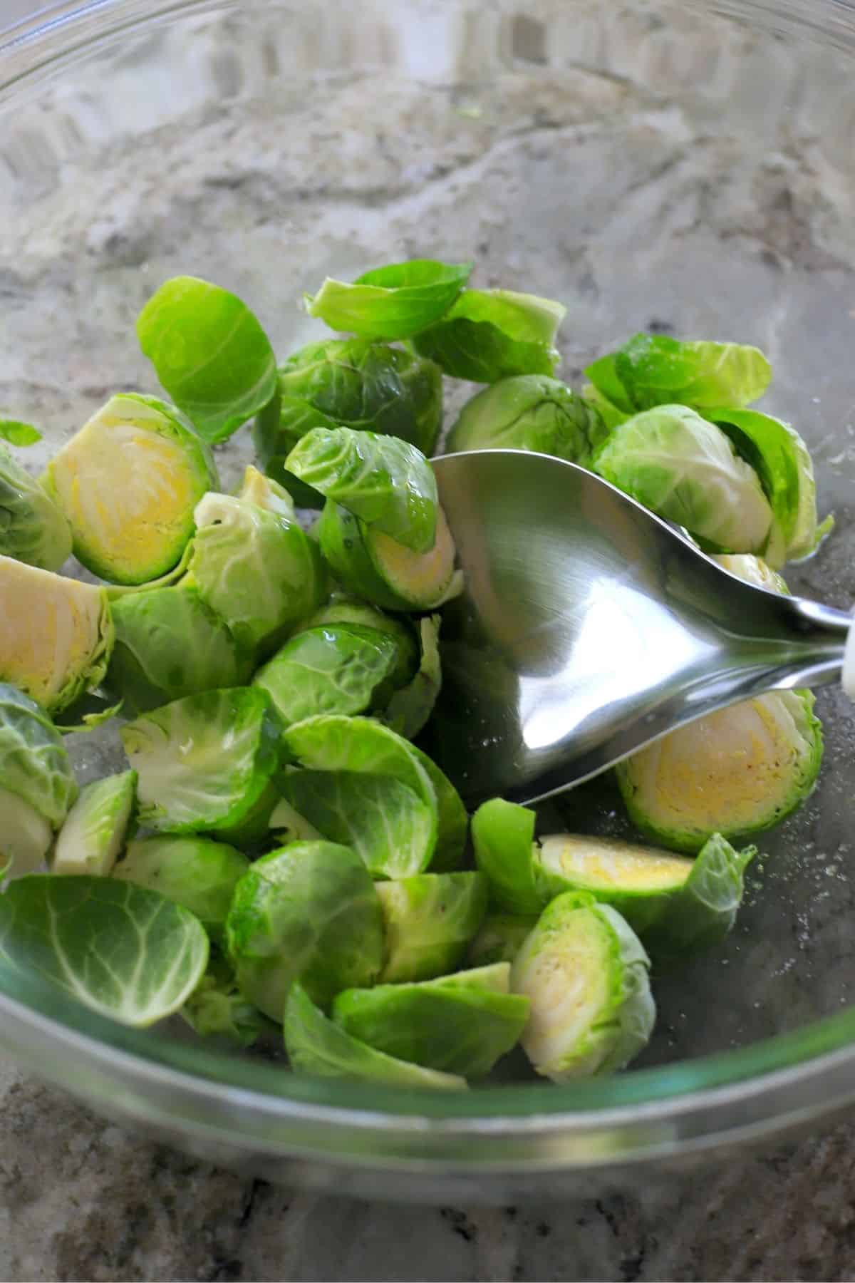 fresh brussel sprouts being tossed in a bowl.