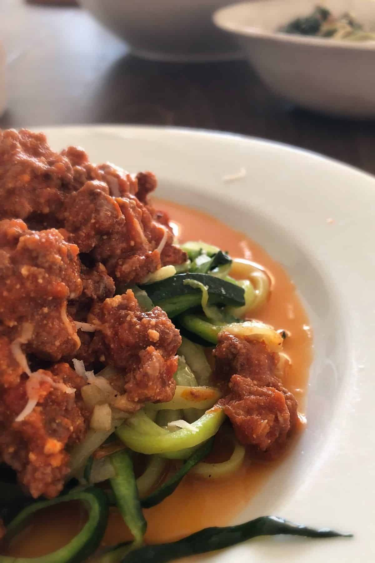 bowl of zucchini noodles topped with meat sauce.