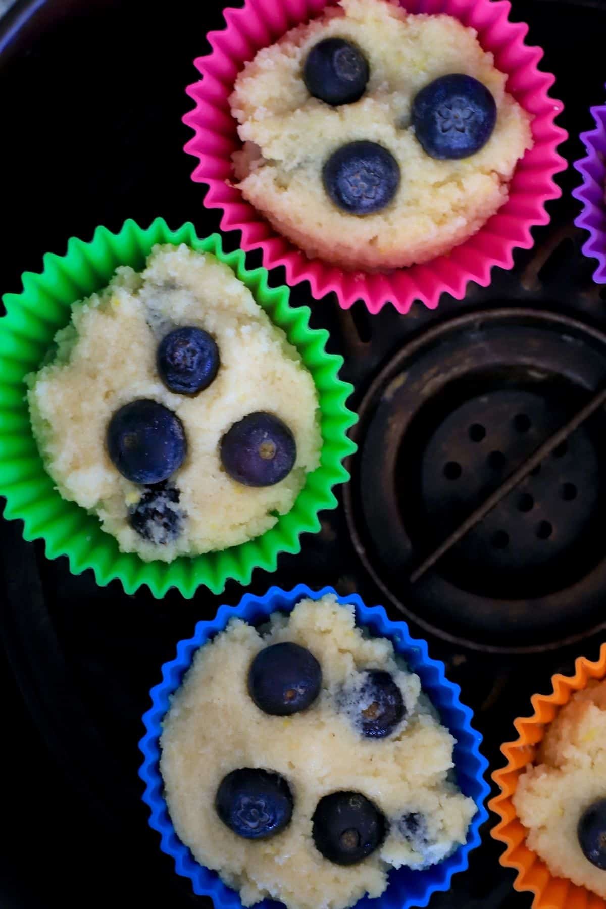 lemon blueberry muffin batter in silicone molds in the air fryer basket.