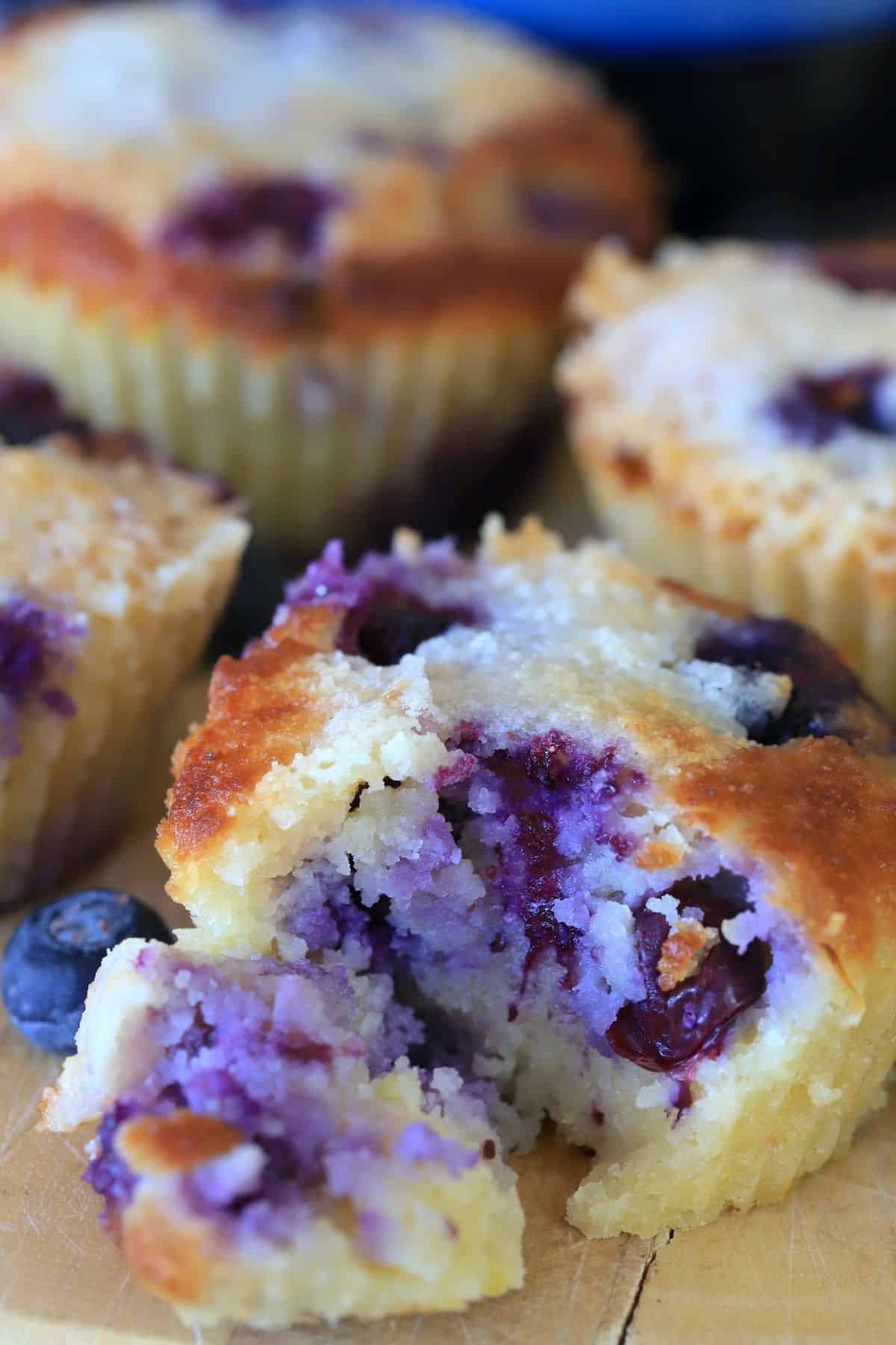 closeup of a muffin with a chunk out of it next to whole muffins.