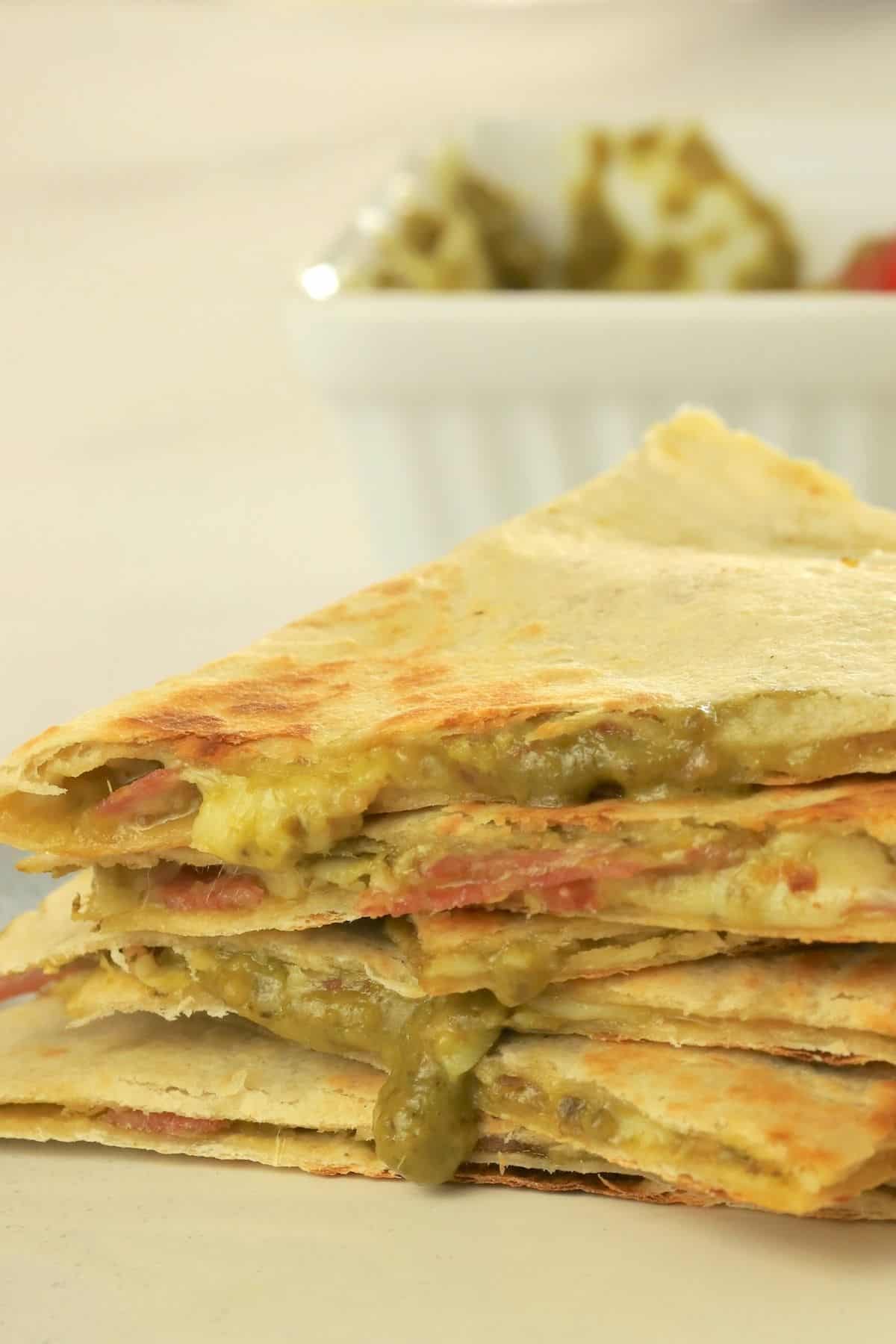 low carb italian quesadillas stacked on top of each other, oozing with pesto and cheese.