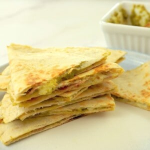 low carb italian quesadillas stacked on top of each other, oozing with pesto and cheese.