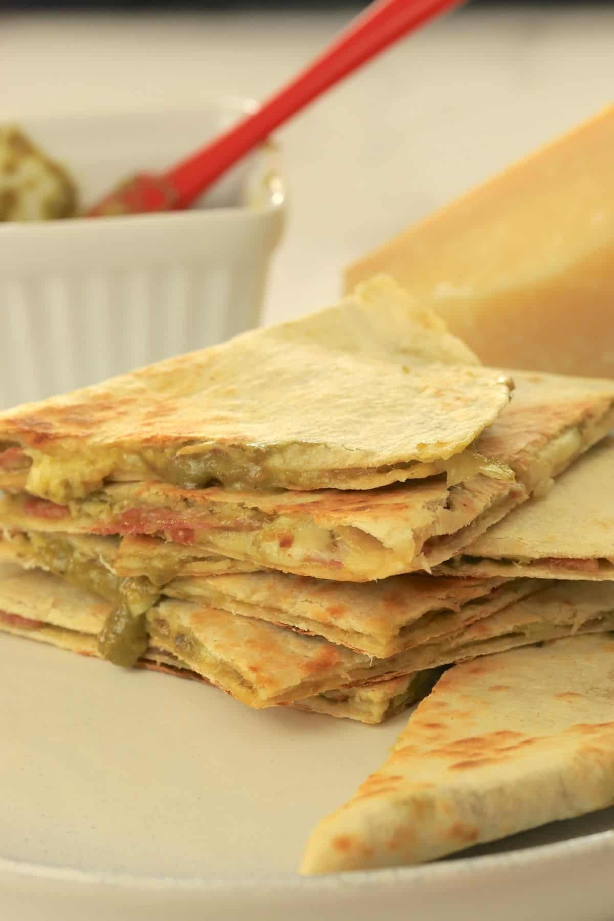 low carb italian quesadillas stacked on top of each other, oozing with pesto and cheese.