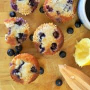 5 lemon blueberry muffins with a half lemon and zester.