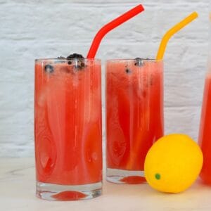 closeup of two glasses full of watermelonade with straws.