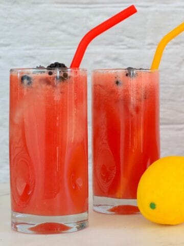 closeup of two glasses full of watermelonade with straws.