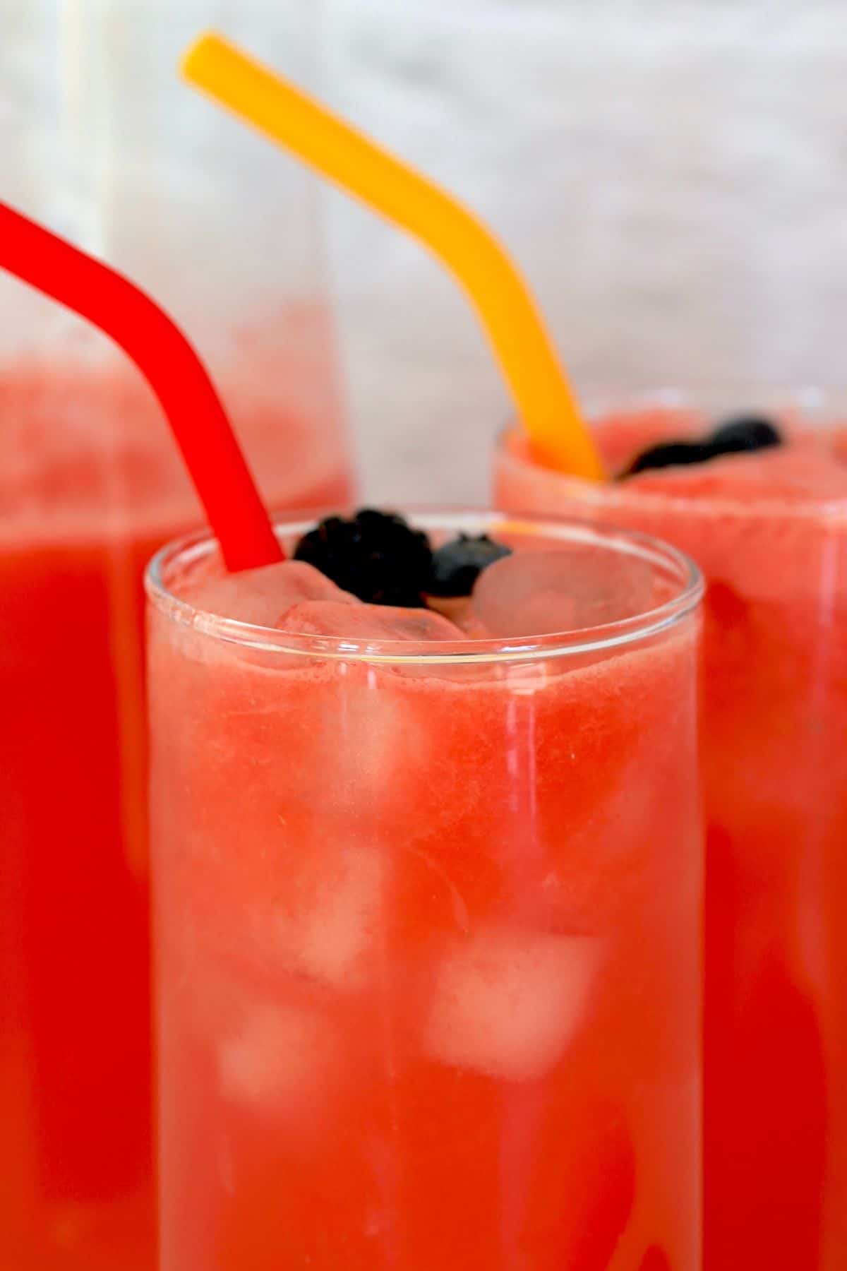 closeup of two glasses full of watermelonade with straws.