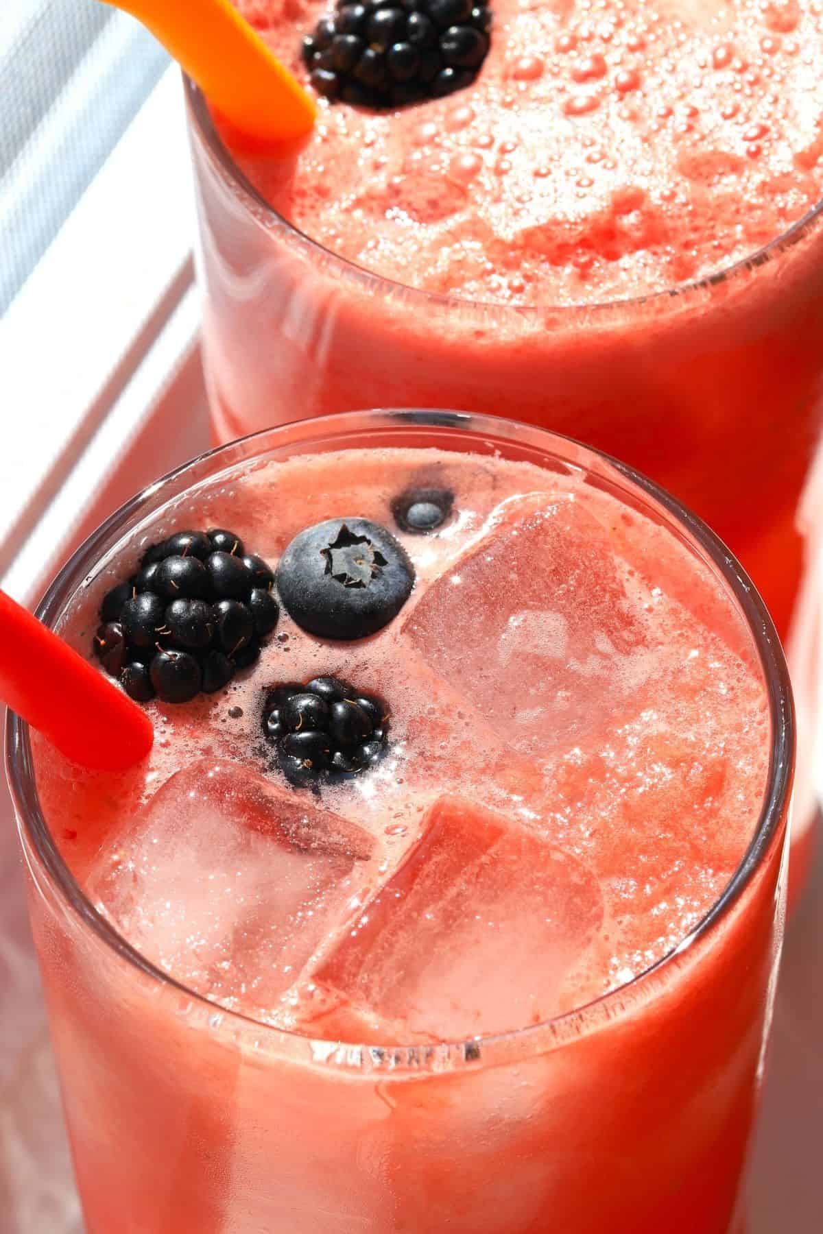 top down view of two highball glasses full with watermelonade and garnished with berries.