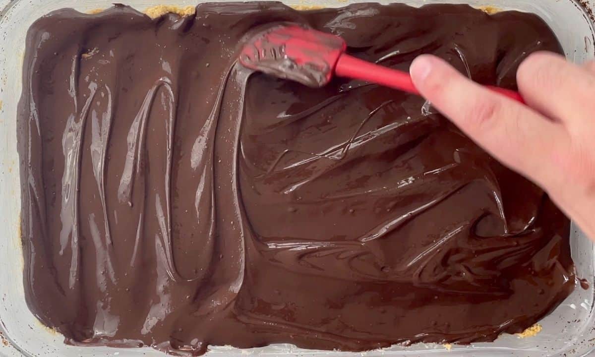 spreading the melted chocolate onto the crust.
