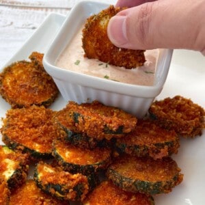 air fried zucchini keto chips on a plate with a dip.