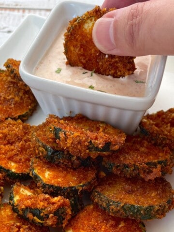 air fried zucchini keto chips on a plate with a dip.