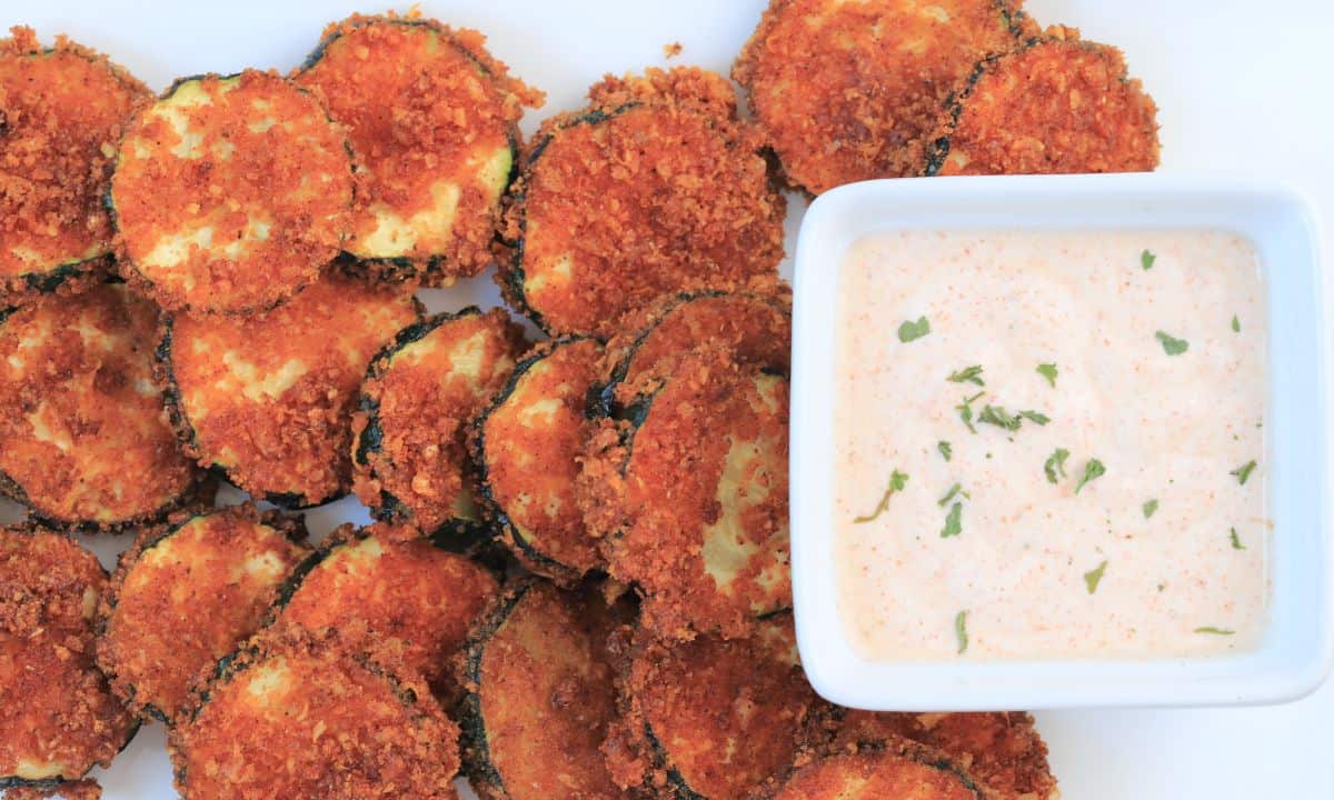 air fried zucchini keto chips on a plate with a dip.