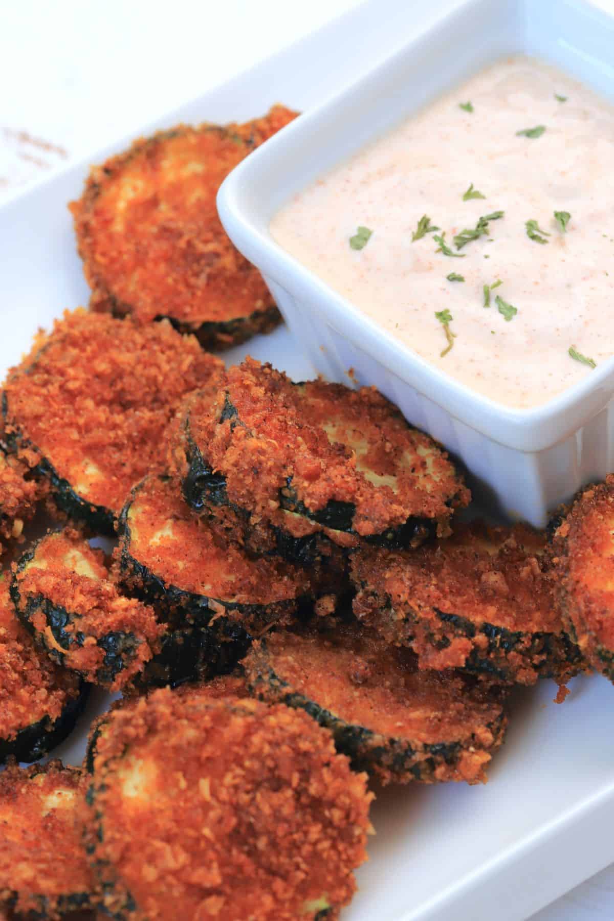 air fried zucchini keto chips on a plate with a dip.