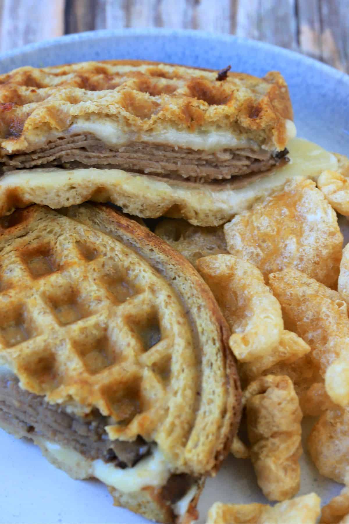 carbonaut waffle sandwich cut in half on a plate with pork rinds.