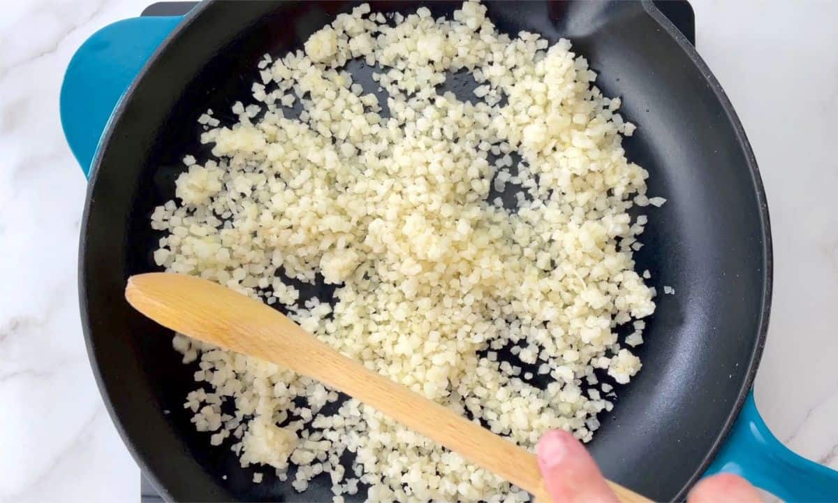 stirring the cauliflower rice in the breakfast skillet.