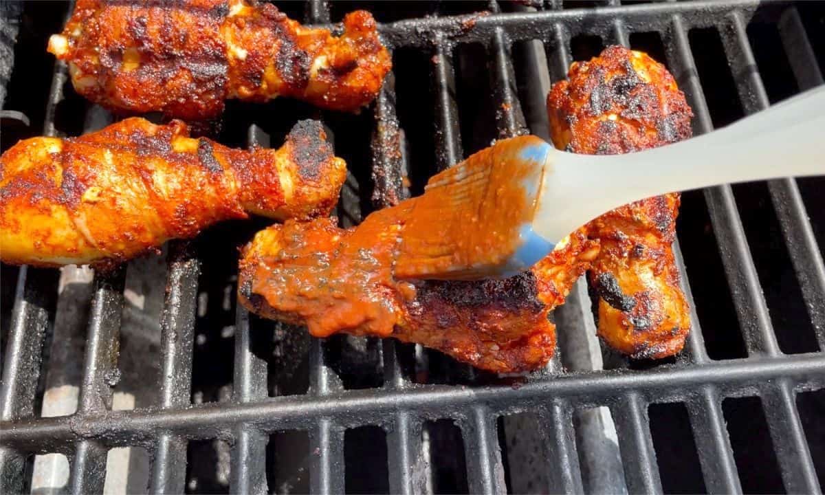 brushing chicken with sauce on the grill.