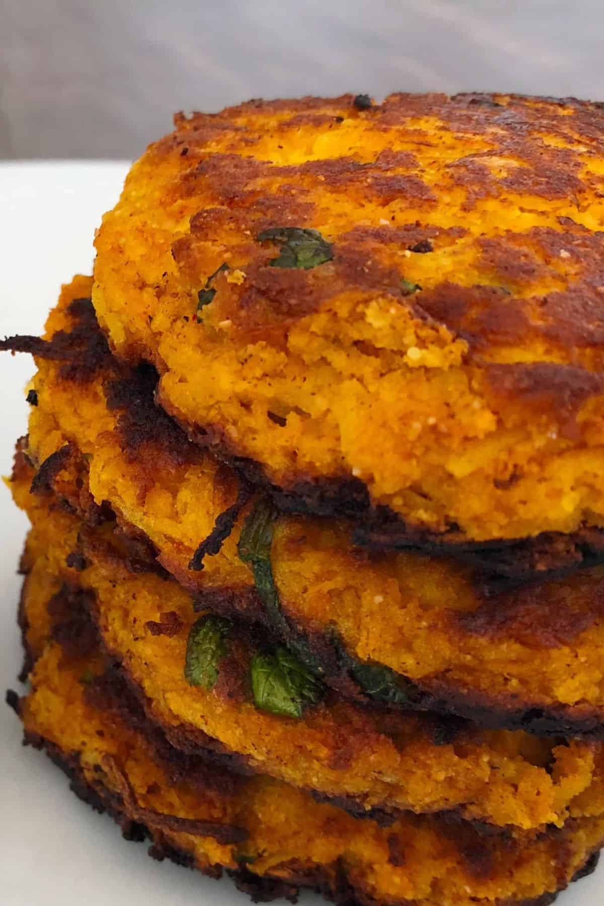 diabetic spaghetti squash fritters stacked on a white plate with a side dip.
