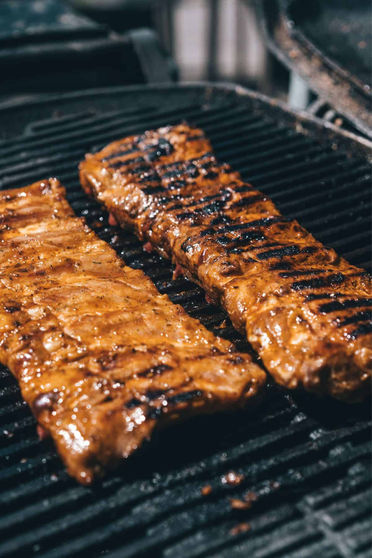 two racks of baby back ribs on a bbq grill.