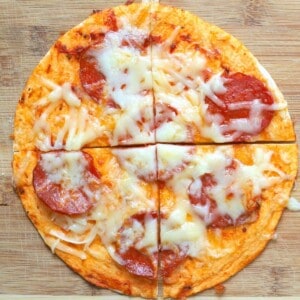 air fryer tortilla pizza topped with pepperoni and cheese on a cutting board.