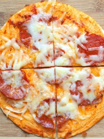 air fryer tortilla pizza topped with pepperoni and cheese on a cutting board.
