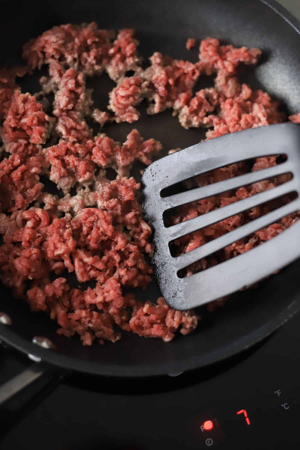 browning ground meat in the skillet with a spatula.