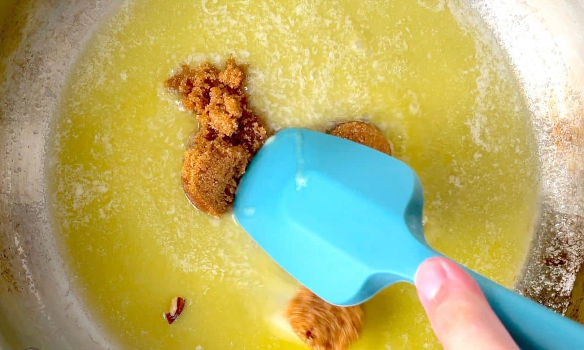 melting the butter with brown sweetener using a blue rubber spatula.