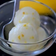 coupe glass with lemon sorbet and a spoon next to a lemon.