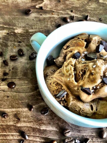 bowl of ice cream coffee with coffee beans sprinkled on the table.