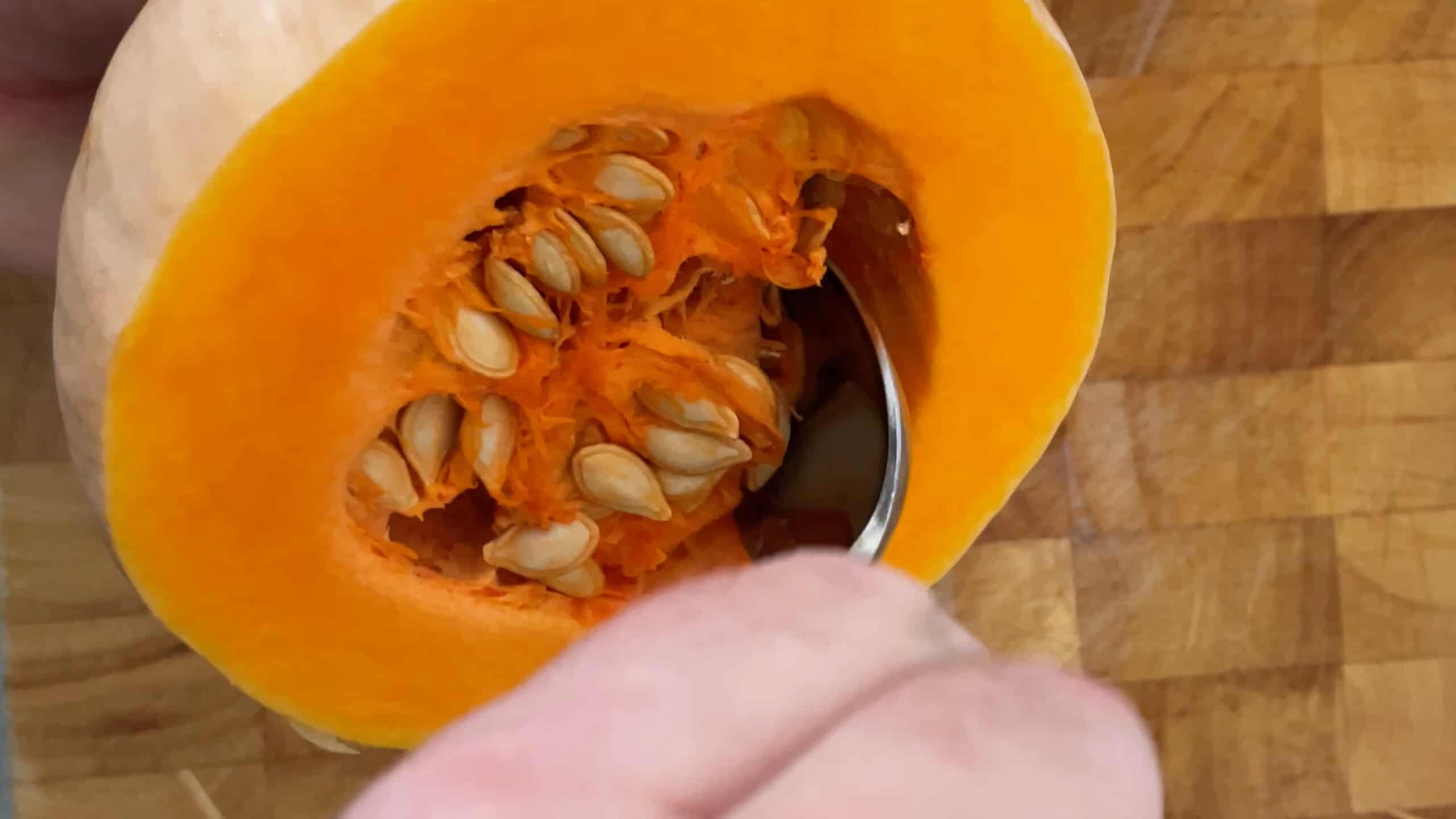 scooping out the seeds and guts from the centre of the butternut squash with a spoon.