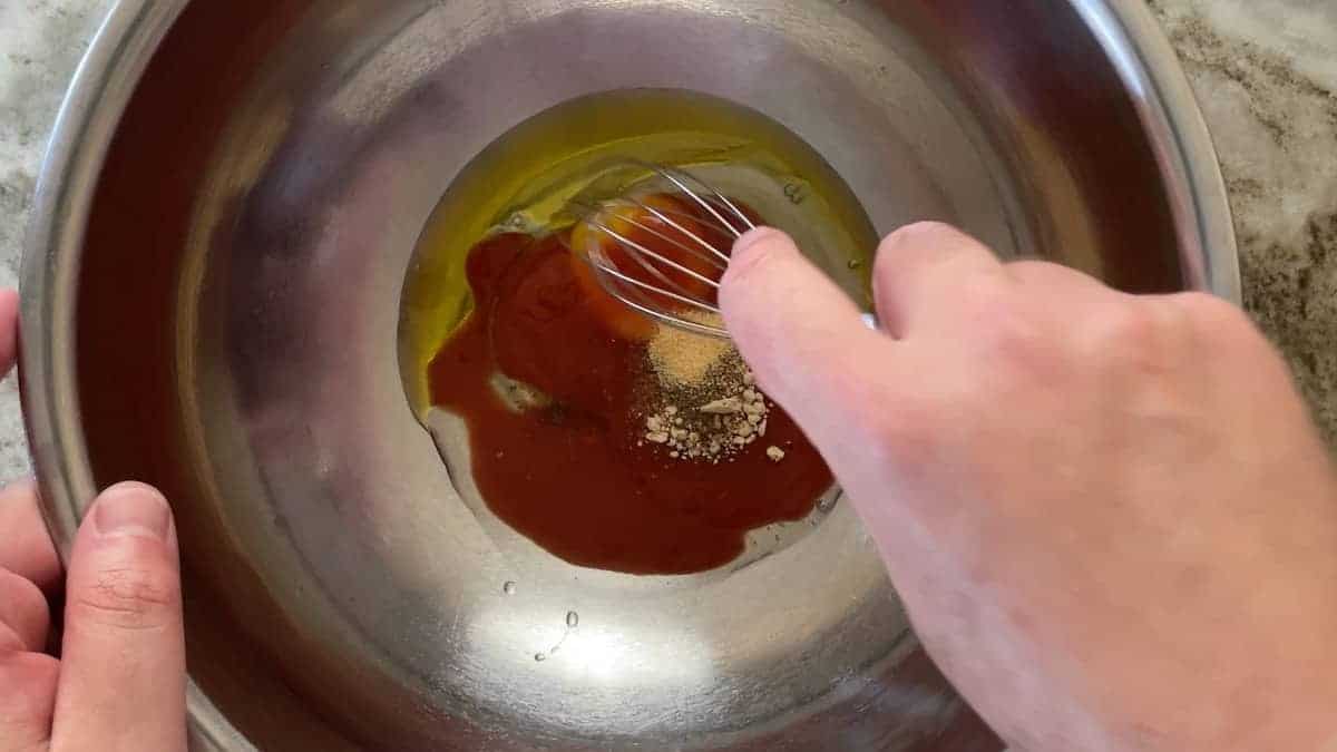 mixing the oil egg and hot sauce in a stainless steel bowl.