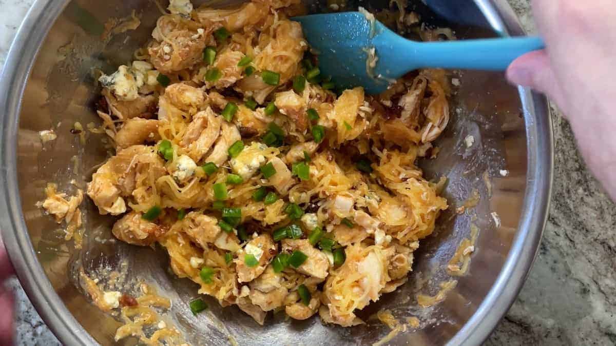 mixing the ingredients in a bowl with a blue rubber spatula.