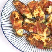 bacon wrapped jalapeno poppers on a blue and white striped plate.
