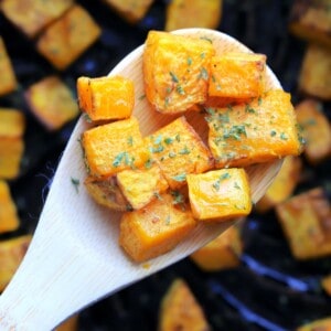 wooden spoon holding cubes of the air fried butternut squash.