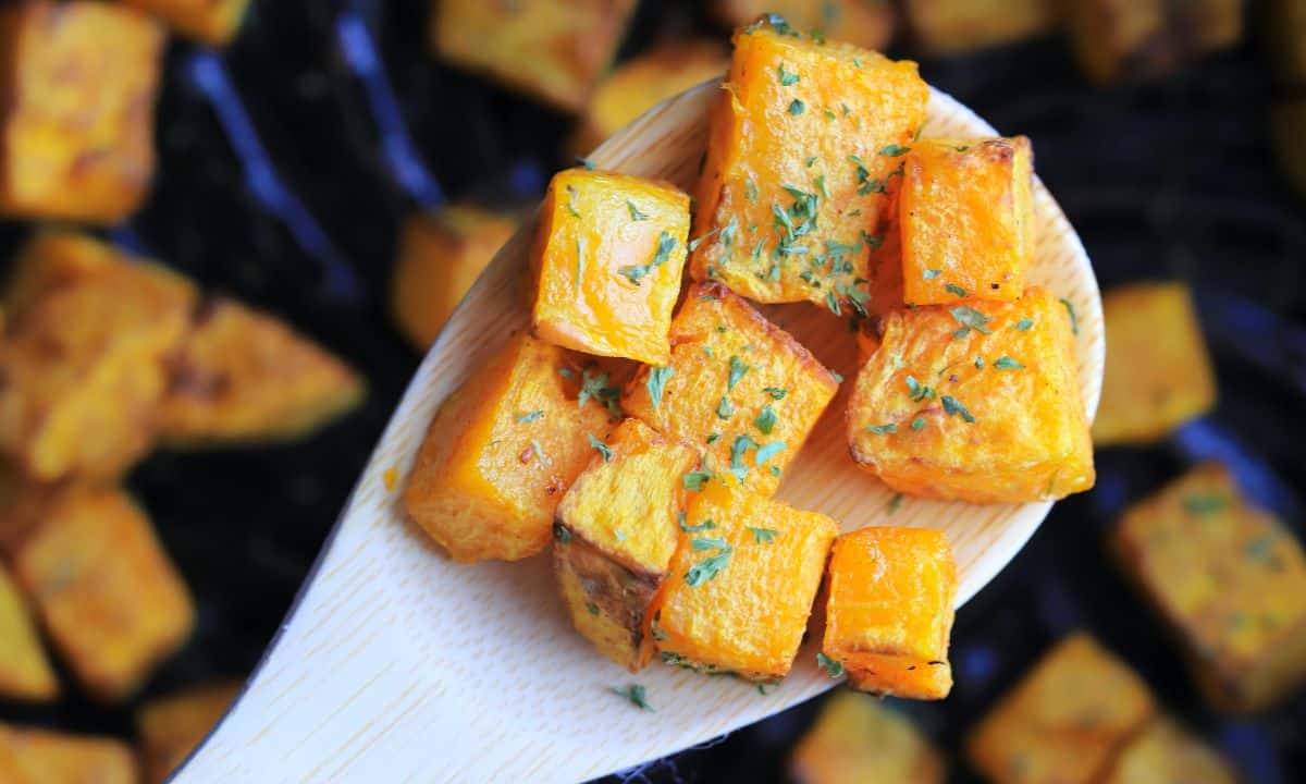 wooden spoon holding cubes of the air fried butternut squash.