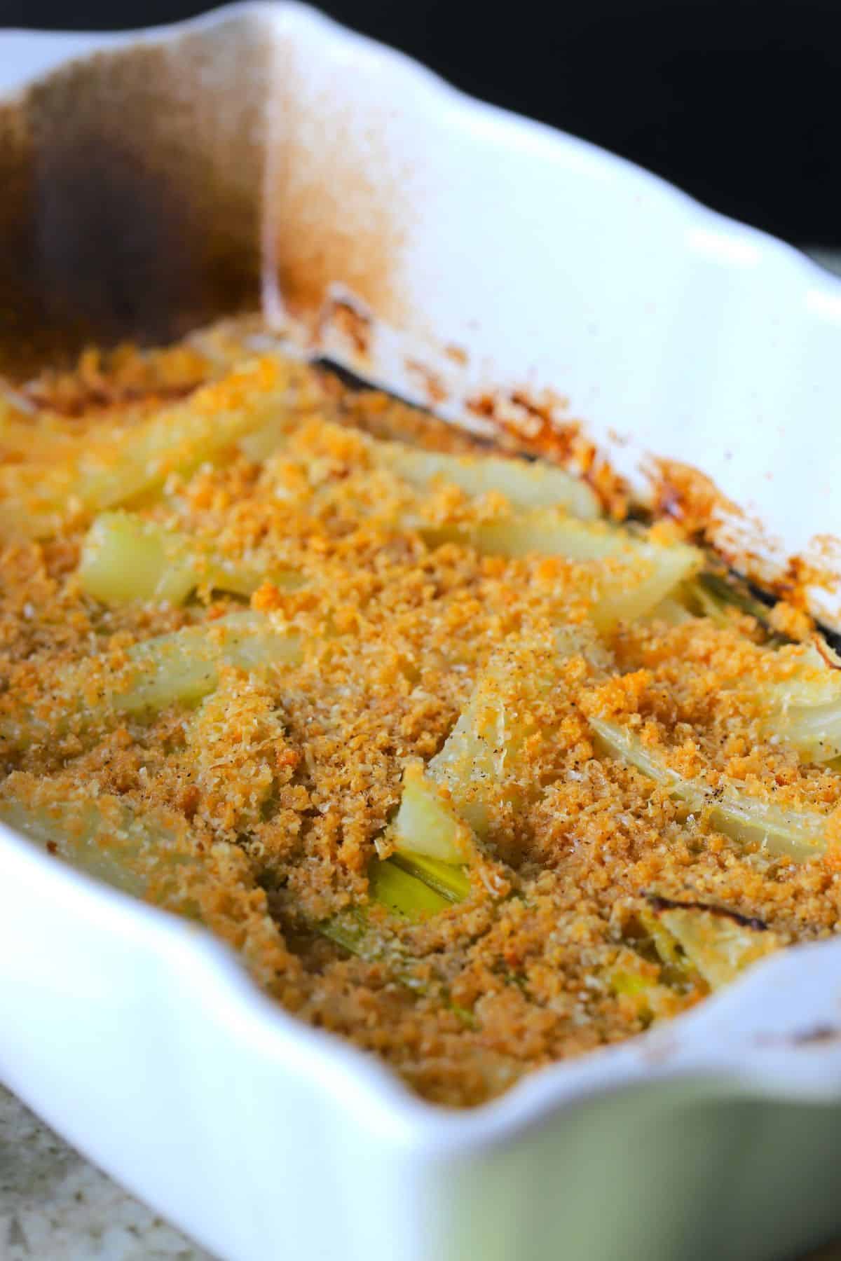 braised fennel and leeks in a white casserole dish topped with a parmesan crust.