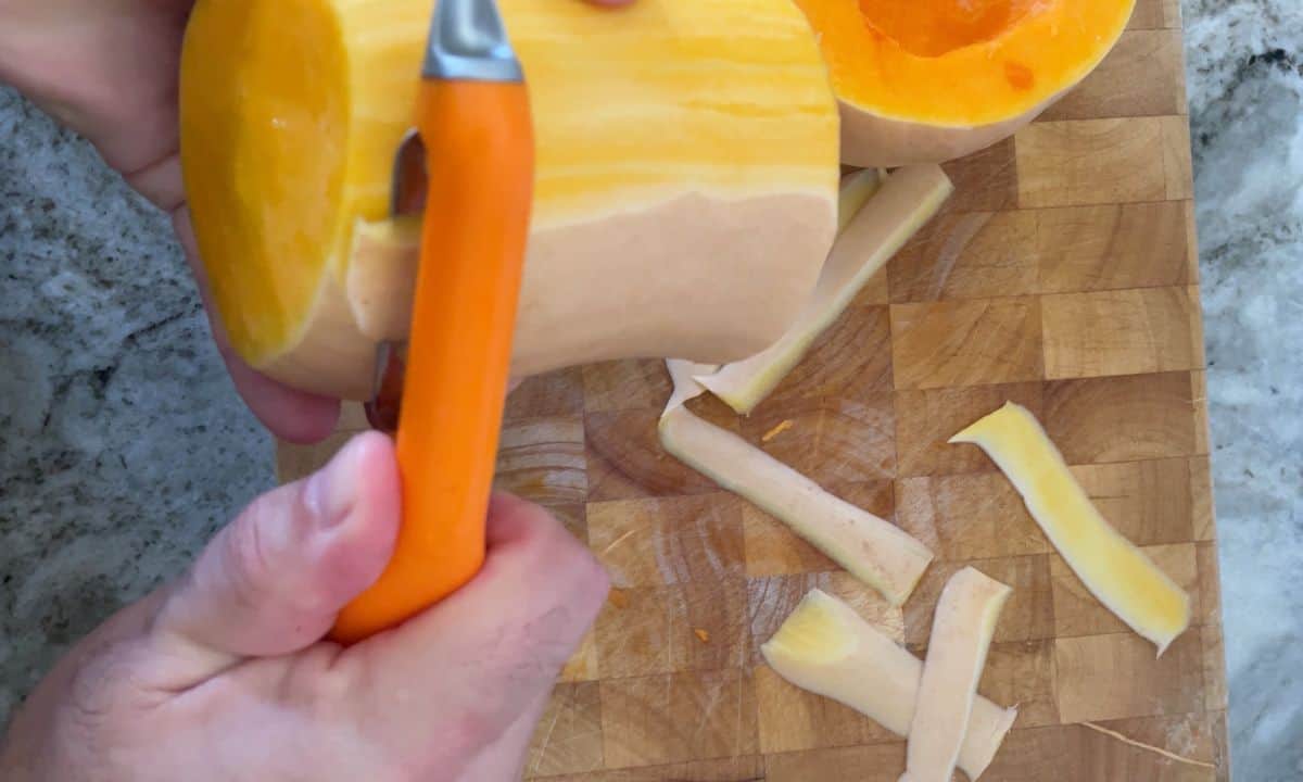 peeling the butternut squash with a vegetable peeler.