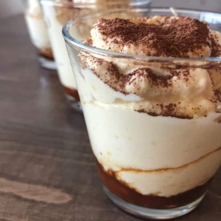 three tiramisu cups lined up on a wooden table