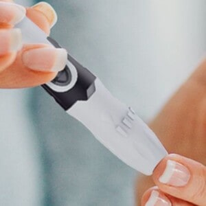 close up of two hands checking blood sugar with a finger prick.